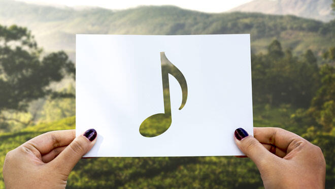 Jessica Mazzoccoli_Lab Experience Nota musicale tenuta tra le mani davanti a un paesaggio naturale