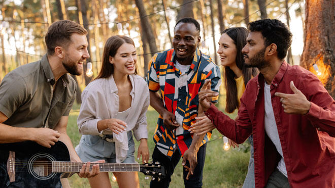 Gruppo di persone canta insieme accompagnato dalla chitarra durante un’esperienza musicale